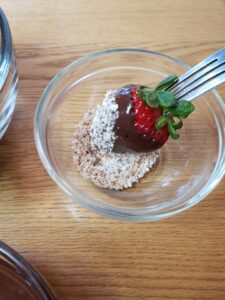 dipping chocolate covered strawberry into crushed almonds