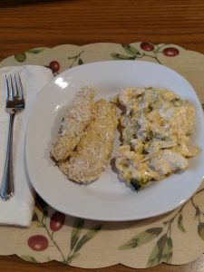 coconut crusted chicken strips and broccoli and cauliflower cheesy bake on white plate